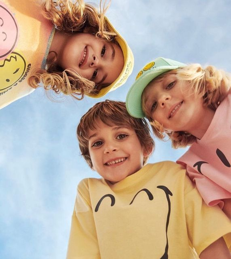 Trois enfants souriants sous un ciel bleu