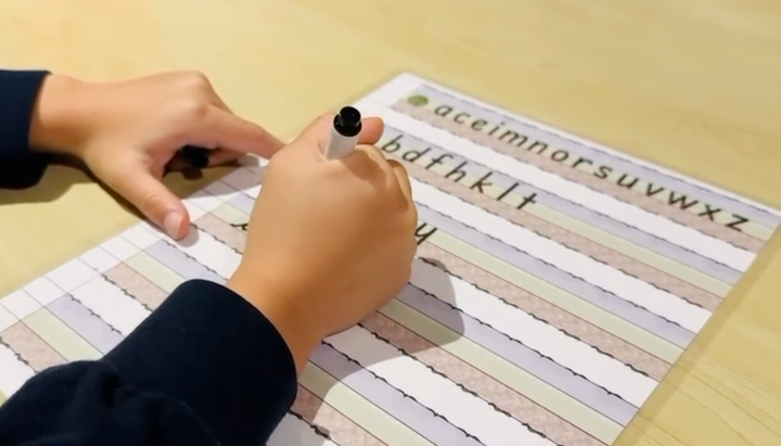Enfant qui s’exerce au feutre sur la feuille d’écriture Entre les lignes