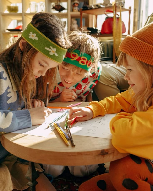 Trois enfants qui écrivent ensemble autour d’une table